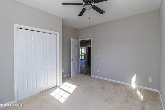 unfurnished bedroom featuring ceiling fan, a closet, and light carpet