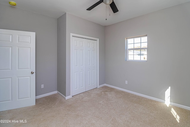 unfurnished bedroom featuring a closet, light colored carpet, and ceiling fan