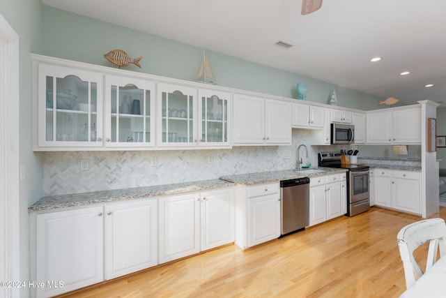 kitchen with tasteful backsplash, stainless steel appliances, sink, light hardwood / wood-style floors, and white cabinets