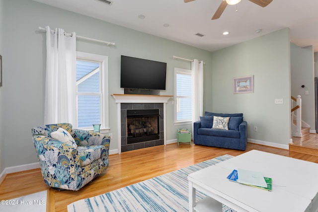 living room featuring a fireplace, wood-type flooring, and ceiling fan