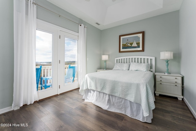 bedroom featuring access to outside, dark wood-type flooring, and a tray ceiling