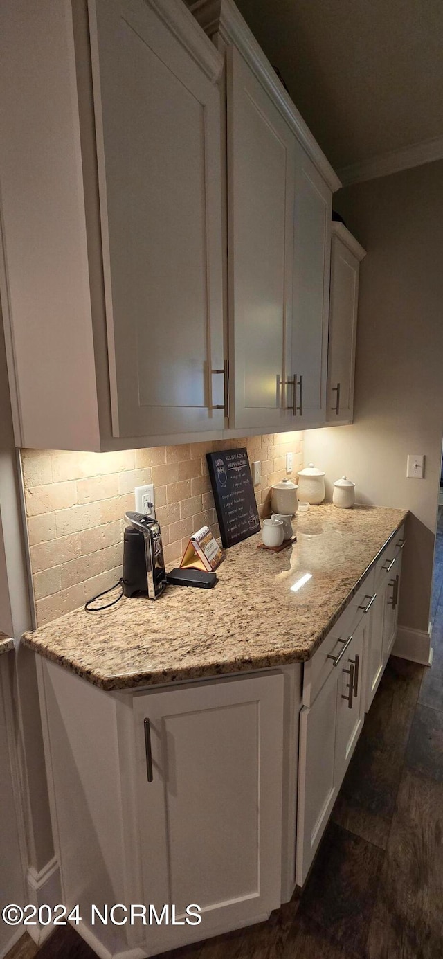 kitchen featuring white cabinetry, ornamental molding, light stone counters, and decorative backsplash