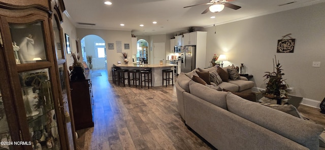 living room with dark hardwood / wood-style flooring, crown molding, and ceiling fan