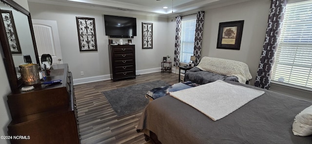 bedroom with ornamental molding, dark hardwood / wood-style floors, and a tray ceiling