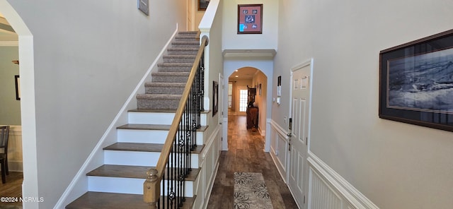 staircase featuring a towering ceiling and hardwood / wood-style floors