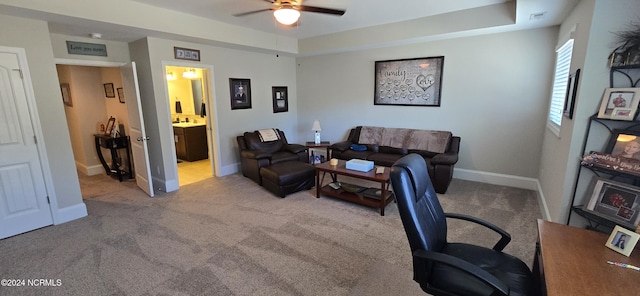 carpeted office with a tray ceiling and ceiling fan