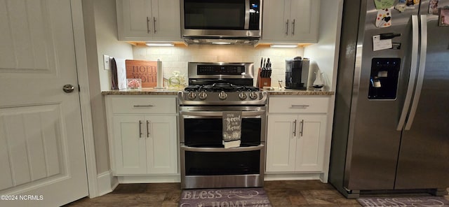 kitchen with light stone countertops, backsplash, stainless steel appliances, and white cabinets