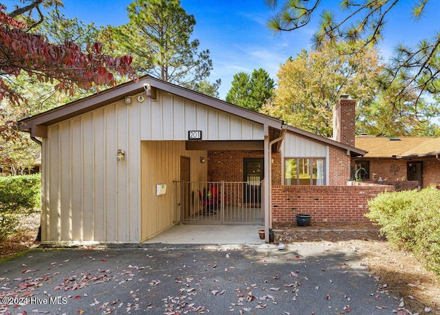 view of front of home with board and batten siding, a chimney, and brick siding