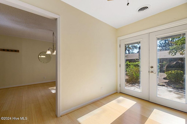 doorway to outside with an inviting chandelier, french doors, light wood-style flooring, baseboards, and visible vents