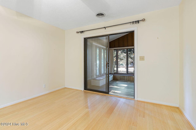 spare room with vaulted ceiling and light wood-type flooring