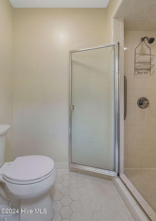 bathroom with toilet, tile patterned flooring, and an enclosed shower