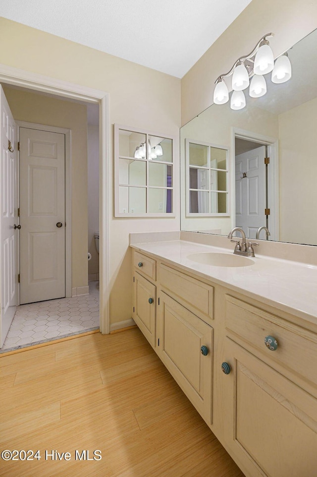 bathroom with vanity, wood finished floors, and toilet