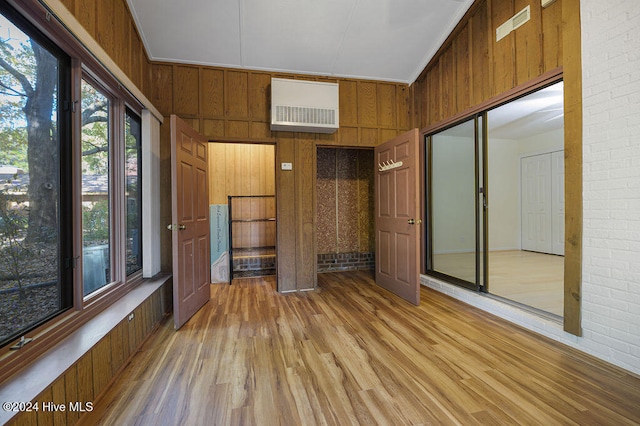 interior space with a towering ceiling, light hardwood / wood-style flooring, wooden walls, and crown molding