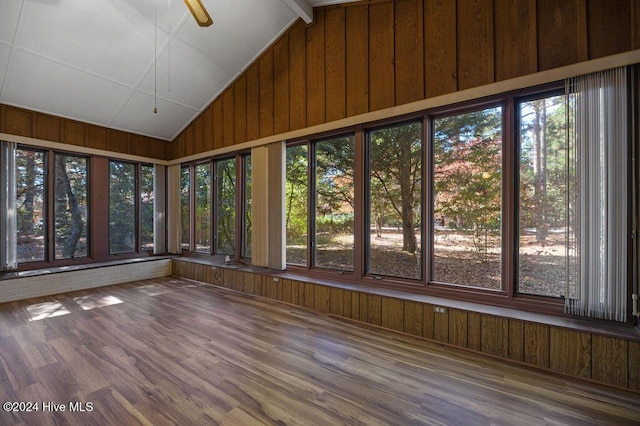 unfurnished sunroom featuring wooden walls, vaulted ceiling, and wood finished floors