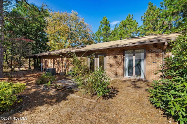 back of house with brick siding and cooling unit