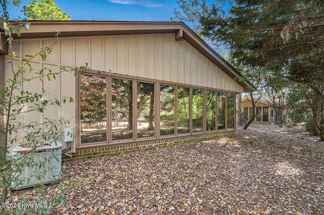 view of home's exterior with central air condition unit and a sunroom