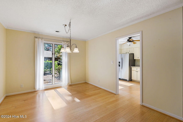 unfurnished dining area featuring a textured ceiling, ornamental molding, light wood-type flooring, and ceiling fan with notable chandelier