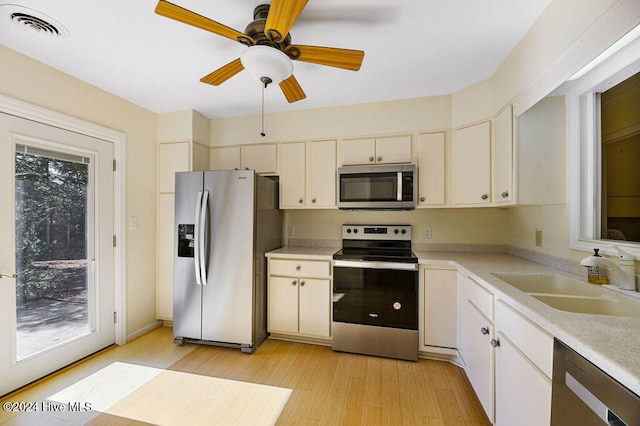 kitchen featuring ceiling fan, appliances with stainless steel finishes, sink, and light wood-type flooring