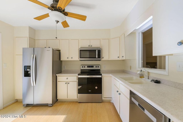 kitchen with appliances with stainless steel finishes, light countertops, light wood-style flooring, a ceiling fan, and cream cabinetry
