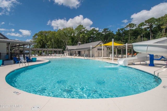 view of swimming pool with a water slide and a patio