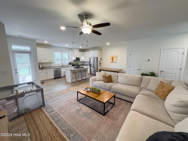 living room featuring sink, light hardwood / wood-style flooring, and ceiling fan