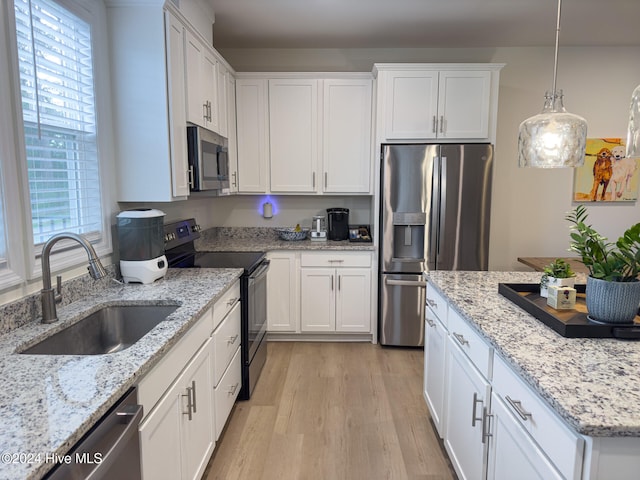 kitchen with sink, appliances with stainless steel finishes, hanging light fixtures, and white cabinetry