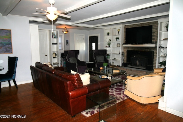 living room with wood-type flooring, a fireplace, ceiling fan, beamed ceiling, and ornamental molding