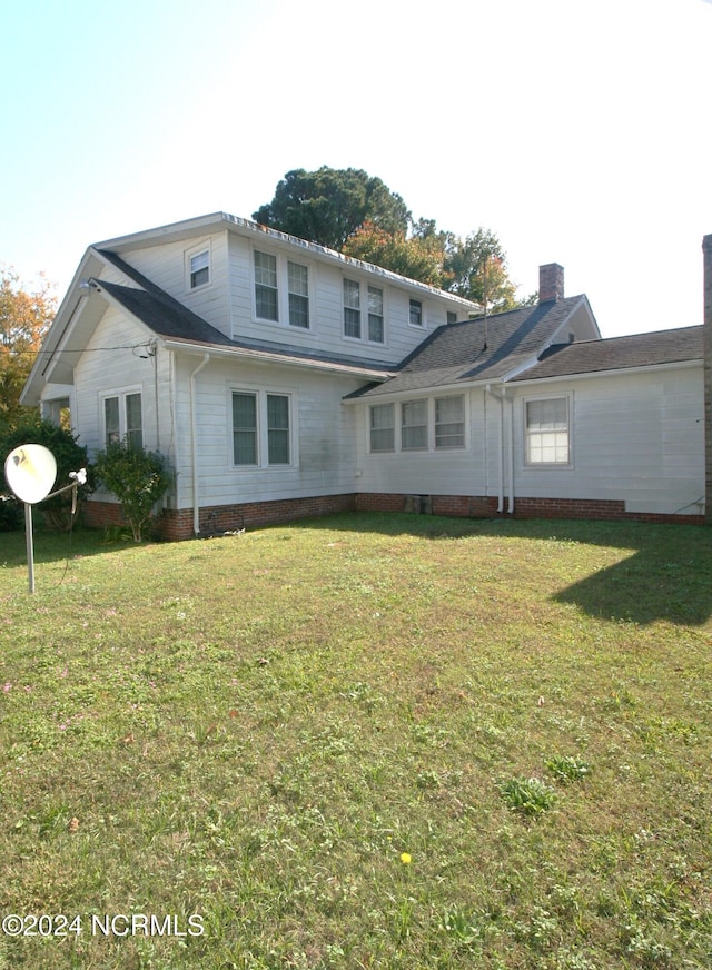 rear view of property featuring a lawn