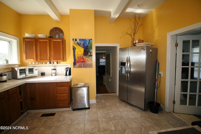 kitchen with beam ceiling, stainless steel fridge with ice dispenser, and tile countertops