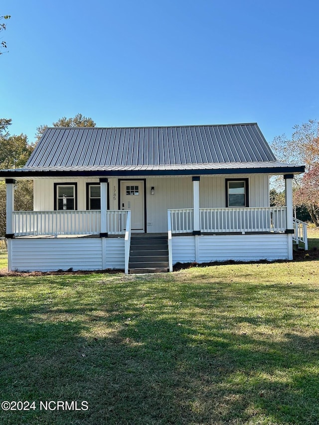 view of front facade with a porch, a front lawn, and metal roof