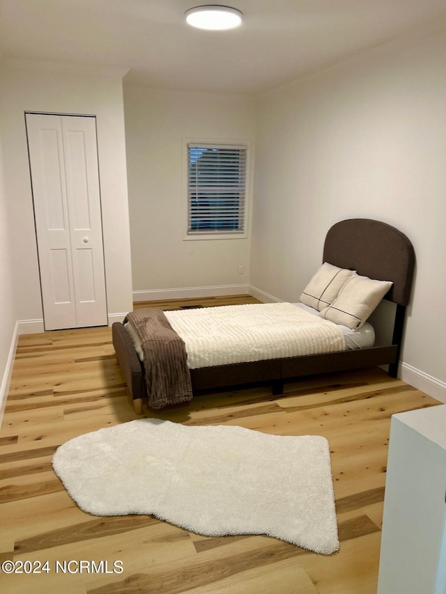 bedroom featuring baseboards, wood finished floors, and a closet