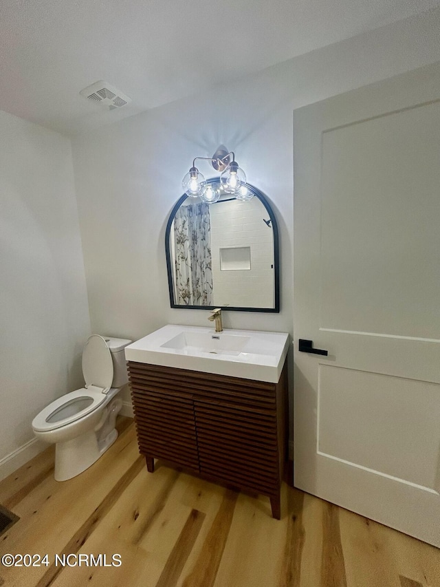 bathroom featuring visible vents, wood finished floors, toilet, and vanity