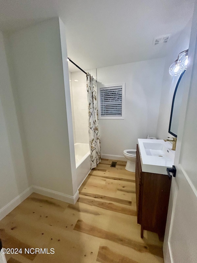 full bathroom with toilet, hardwood / wood-style floors, shower / tub combo with curtain, and vanity