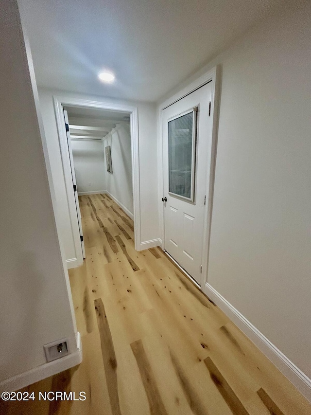 hall with baseboards and light wood finished floors