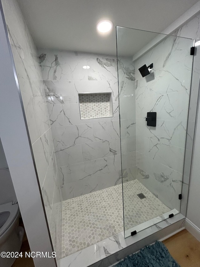 bathroom with a tile shower and toilet