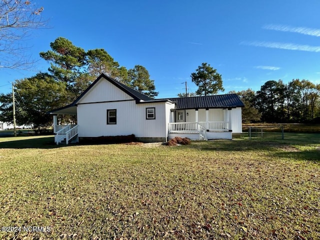 rear view of house with a porch, a yard, and metal roof