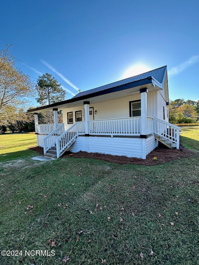 view of front facade with a front lawn, covered porch, and metal roof