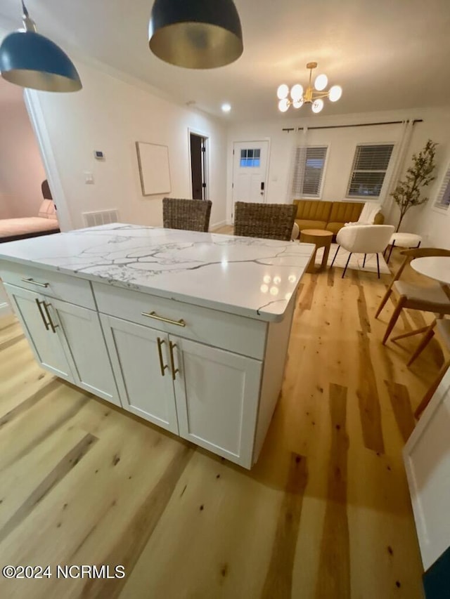 kitchen featuring an inviting chandelier, a kitchen island, visible vents, light wood-style floors, and white cabinetry