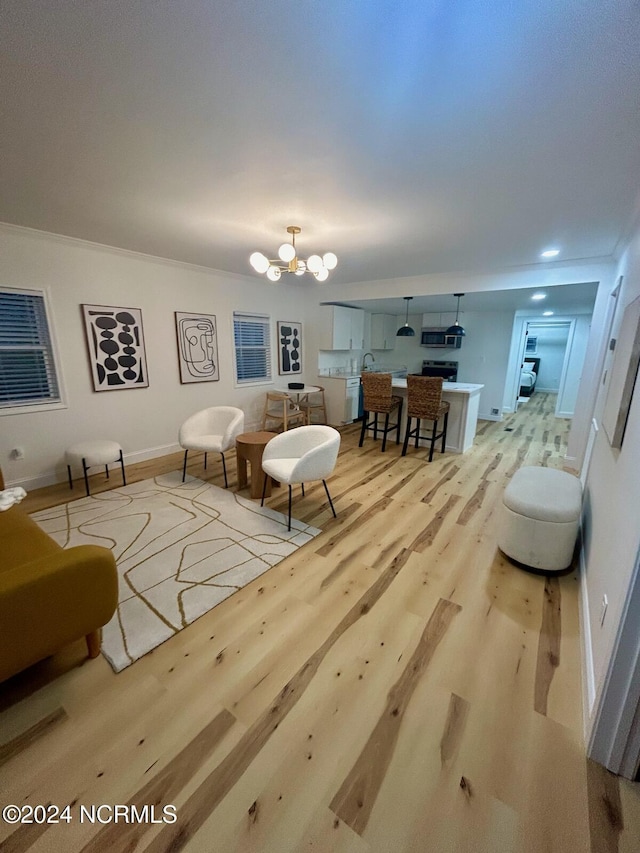 living area featuring an inviting chandelier, light wood-style flooring, and baseboards