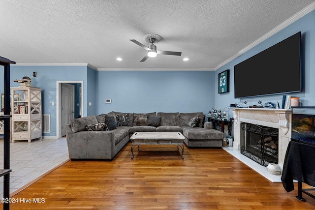 living room featuring light hardwood / wood-style floors, ornamental molding, and a textured ceiling