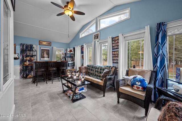 living room with bar area, ceiling fan, and vaulted ceiling