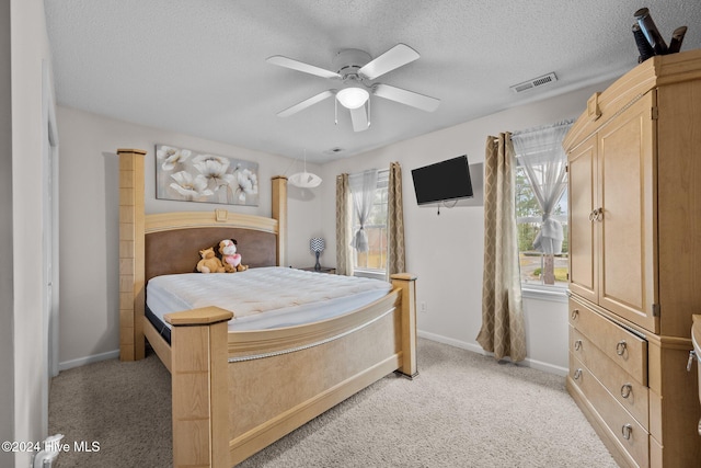 bedroom featuring a textured ceiling, ceiling fan, and light carpet