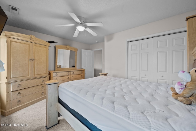 bedroom featuring a textured ceiling, ceiling fan, light carpet, and a closet