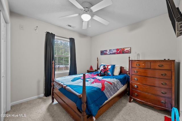 carpeted bedroom with ceiling fan and a textured ceiling