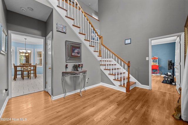 stairs with hardwood / wood-style floors, a towering ceiling, and a chandelier