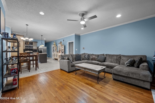 living room with ceiling fan with notable chandelier, light hardwood / wood-style floors, a textured ceiling, and ornamental molding