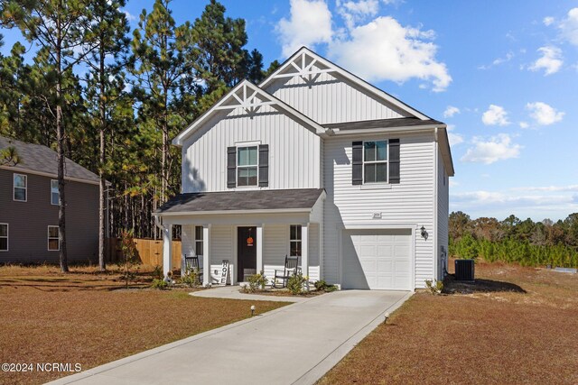 view of front facade featuring central air condition unit, covered porch, and a garage