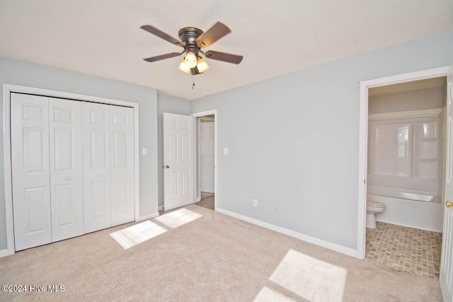 unfurnished bedroom featuring light carpet, a textured ceiling, ceiling fan, connected bathroom, and a closet