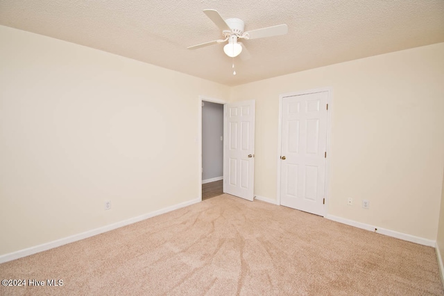 unfurnished bedroom featuring ceiling fan, light colored carpet, and a textured ceiling