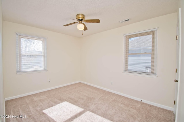 unfurnished room with ceiling fan, light colored carpet, and a textured ceiling